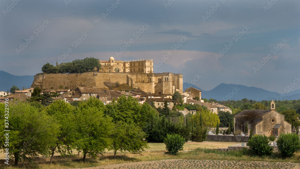 View of the castle of Grignan in Provence under a busy sky