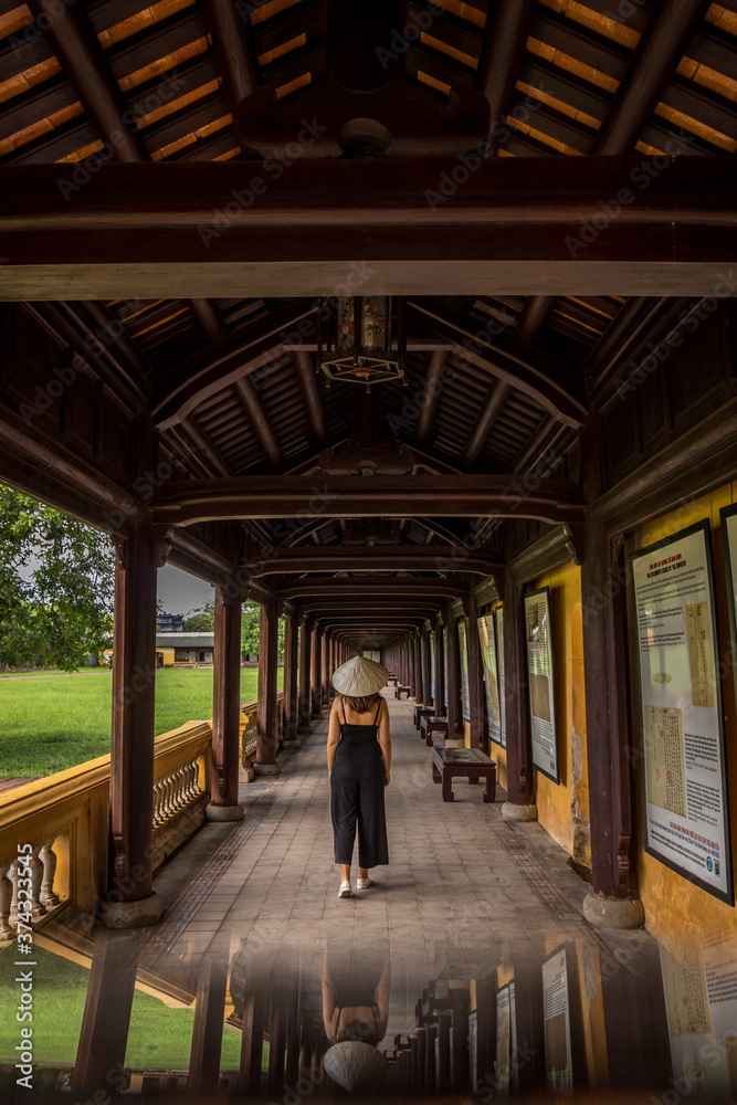 Girl walking with vietnamese hat through the imperial palace of Hue