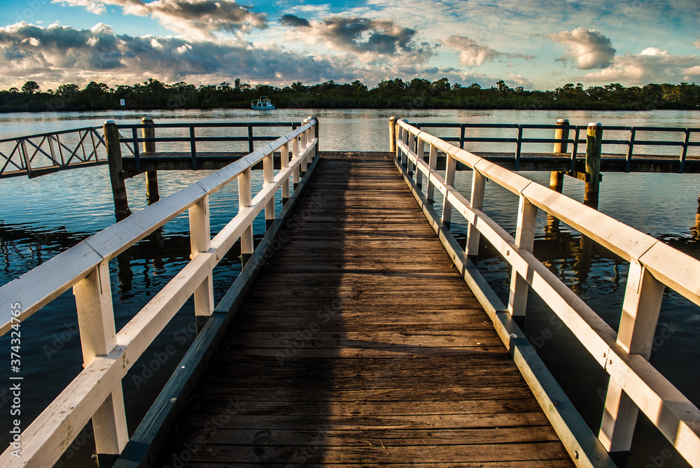 Fototapeta premium Wooden Jetty into the distance over water at sunrise