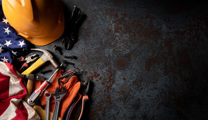 Happy Labor day concept. American flag with different construction tools on dark stone background, with copy space for text.