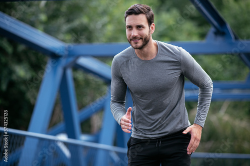 Young man jogging in the city. Happy athlete training outdoors.