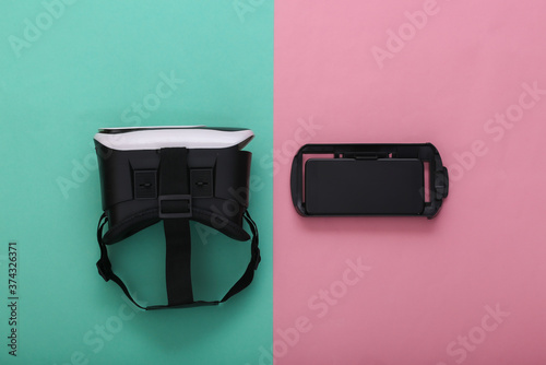 Virtual reality headset and smartphone on pink blue pastel background. Modern gadgets. Top view
