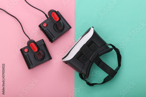 Virtual reality headset and retro joysticks on pink blue pastel background. Entertainment, video game. Top view