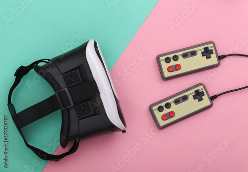 Virtual reality headset, retro gamepads on pink blue pastel background. Entertainment, 3d video game. Top view