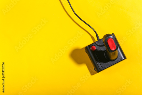 Old joystick on yellow background with shadow. Retro gaming. Top view