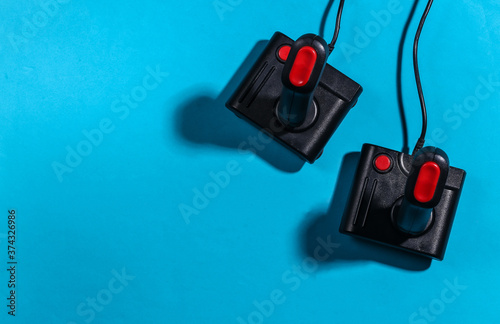 Two retro joysticks on a blue background with a shadow. Retro gaming. Top view
