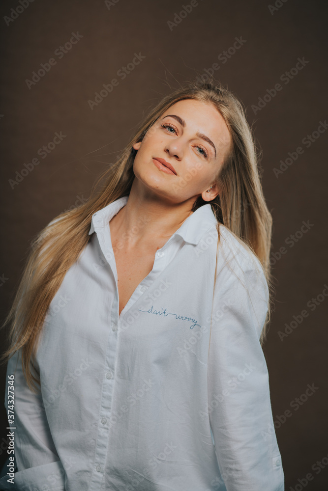 An attractive caucasian blonde female in a white shirt posing on a brown background
An attractive caucasian blonde female in a white shirt posing on a brown background