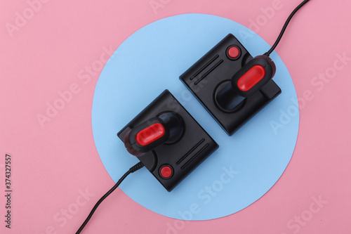 Retro joysticks on pink background with blue circle. Conceptual studio shot. Minimalism. Top view
