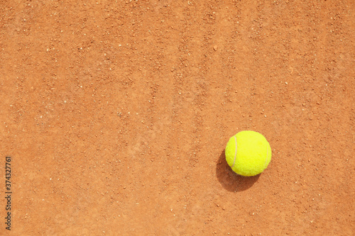 Light green tennis ball on clay court, space for text © Atlas