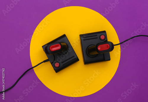Retro joysticks on purple background with yellow circle. Conceptual studio shot. Minimalism. Top view