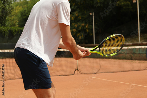 Young man playing tennis on clay court