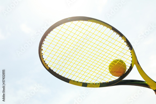 Tennis racquet with tennis ball against sky background © Atlas