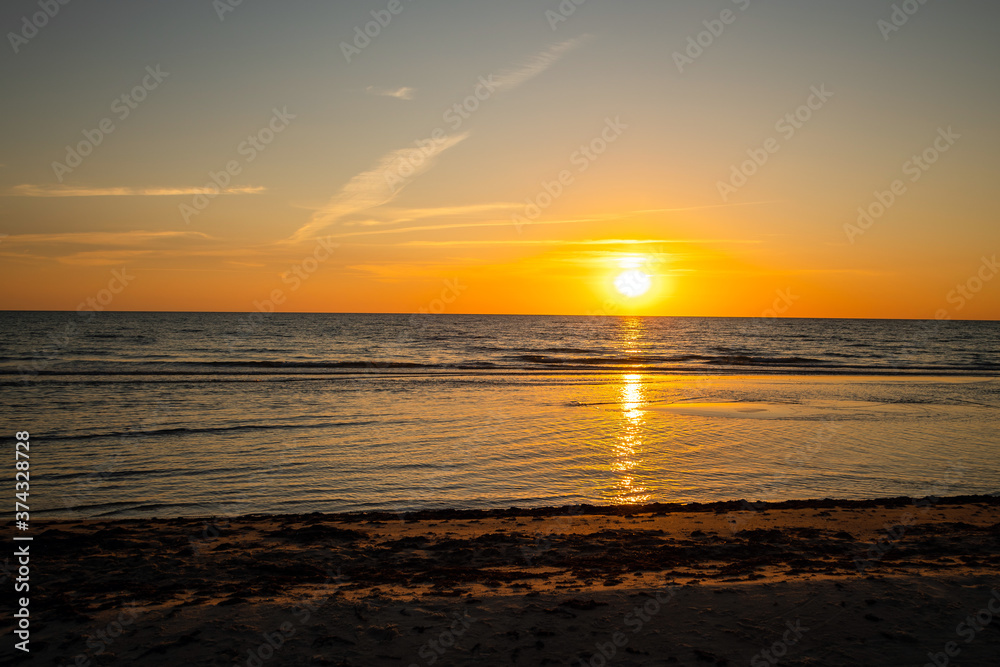 Beautiful golden sunset at the beach. Sun setting into the sea on tranquil evening. Nobody Beautiful golden sunset at the beach. Sun setting into the sea on tranquil evening. Nobody
