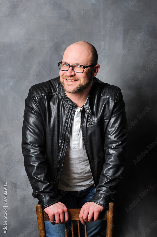 A positive Caucasian male looking into the camera, leaning on the back of a chair. A positive Caucasian male looking into the camera, leaning on the back of a chair.