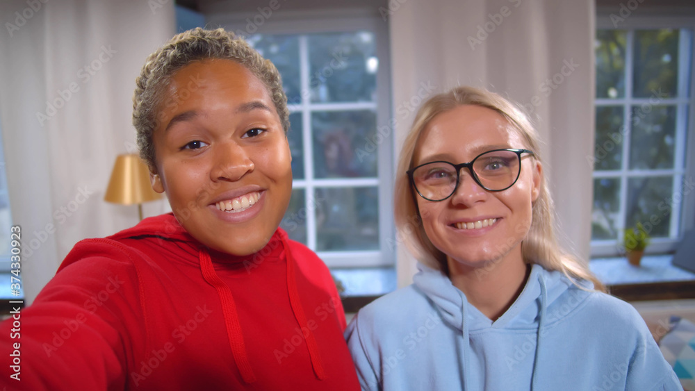 Two beautiful diverse happy girlfriends taking selfies or recording video for blog on social media Two beautiful diverse happy girlfriends taking selfies or recording video for blog on social media