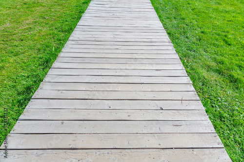 A path made of wooden planks for walking pedestrians in a modern green city park