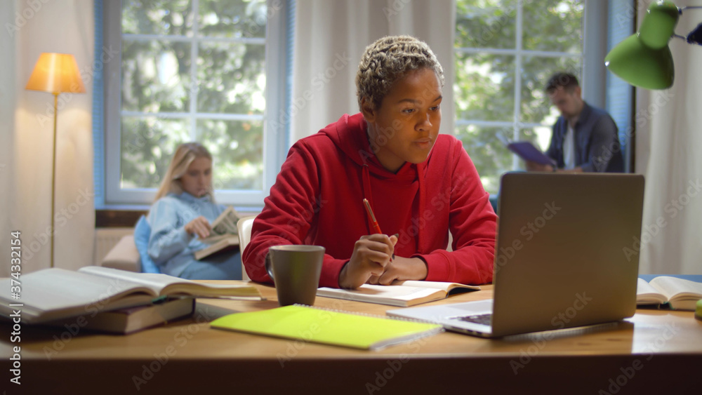 Portrait of african girl studying at desk using laptop at university dorm Portrait of african girl studying at desk using laptop at university dorm
