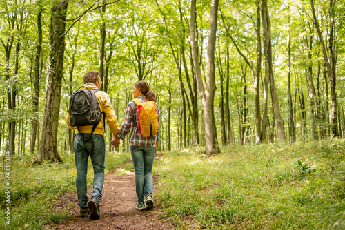 male and female backpackers walking through a forest holding hands