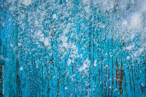 Snow-covered wooden blue table with peeling paint