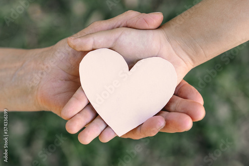 Childs hand and old hand grandmother hold heart. 