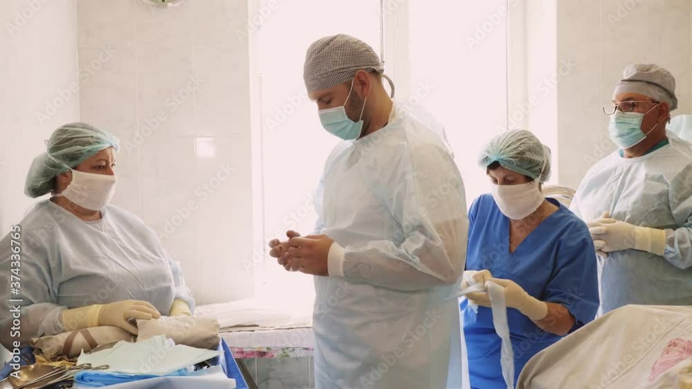 nurse helping surgeon put on protective suit. preparation for the operation. medicine. surgery and resuscitation in hospital. covid-19 pandemic nurse helping surgeon put on protective suit. preparation for the operation. medicine. surgery and resuscitation in hospital. covid-19 pandemic