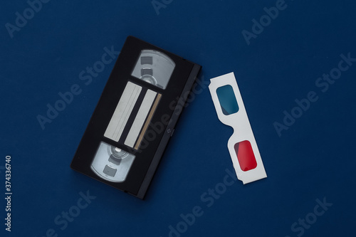 Anaglyph 3D glasses and video cassette on classic blue background. Retro media. Color 2020. Tiop view photo