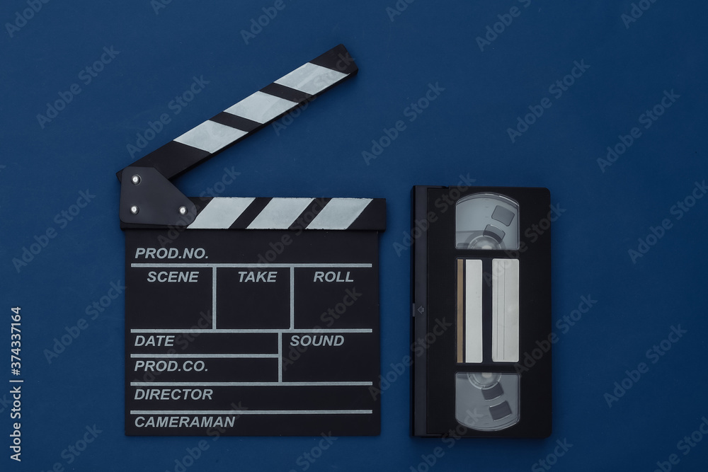 Movie clapper board with video cassette on classic blue background. Filmmaking, Movie production, Entertainment industry. Color 2020. Top view