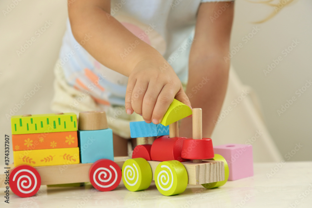 Toddler girl playing with wooden train made from wooden blocks - educational toys for preschool and kindergarten child. Toddler girl playing with wooden train made from wooden blocks - educational toys for preschool and kindergarten child.