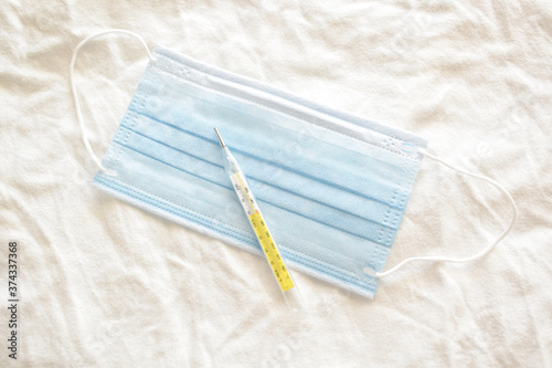 Medical mask or surgical mask and thermometer. Healthcare and medical concept.