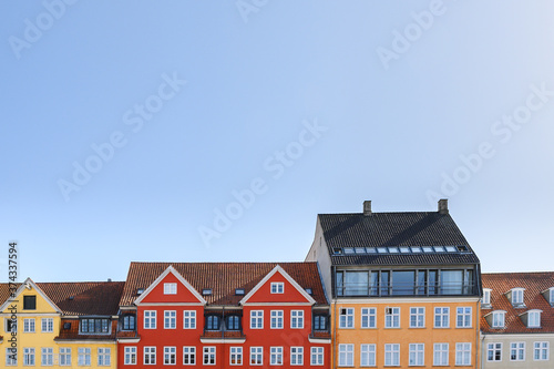 Photography Colorful houses in yellow, red and orange of the Nyhaven in Copenhagen Denmark photographed frontally on a sunny day with a bright blue sky