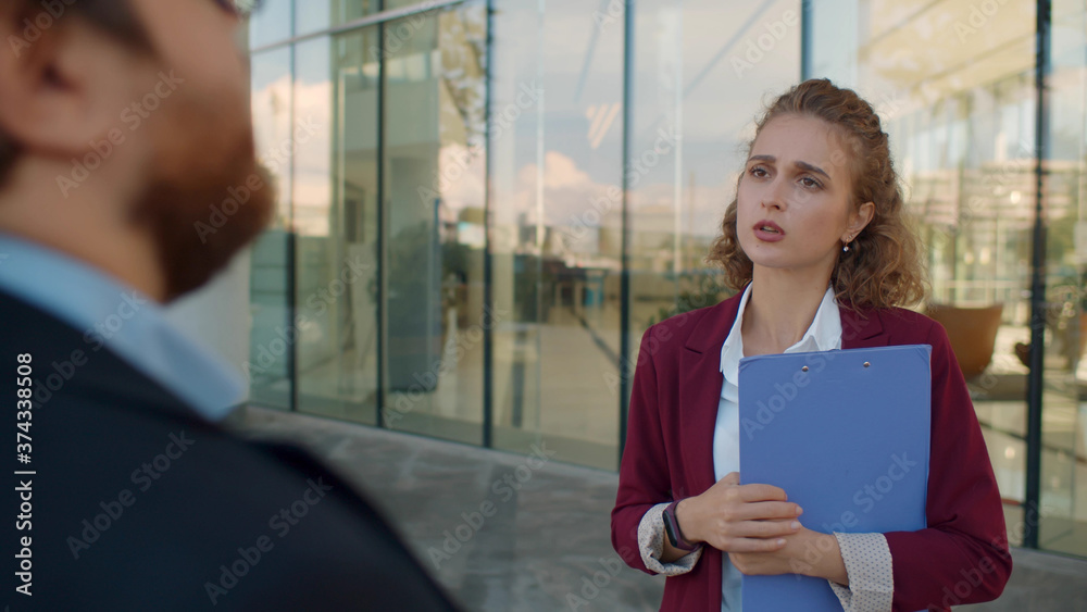 Back view of businessman talking to elegant female manager standing outdoors Back view of businessman talking to elegant female manager standing outdoors