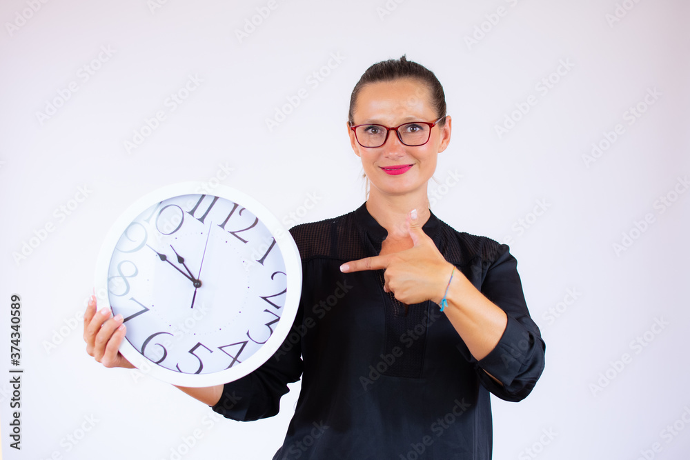 Pretty businesswoman with glasses pointing a big clock Pretty businesswoman with glasses pointing a big clock