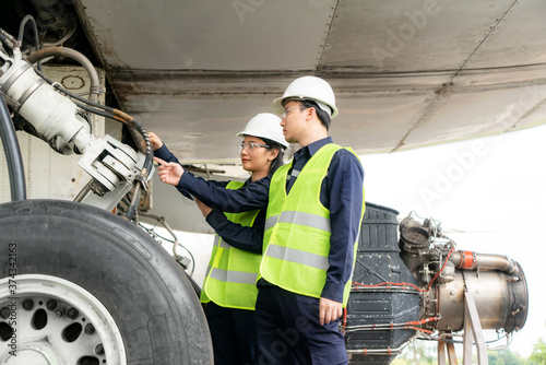 Asian man and woman engineer maintenance airplane team repairs, fixes, modernization and renovation in front airplane from  in airport..