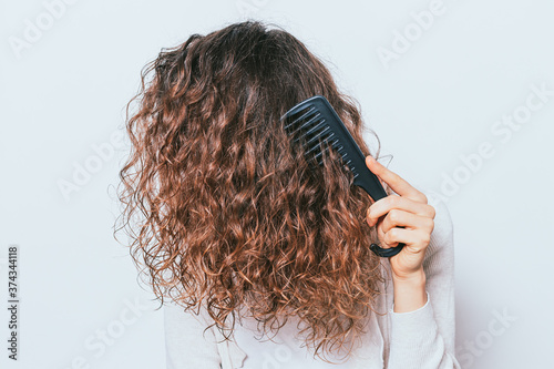 Woman wearing white shirt combing her tangled curly hair photo