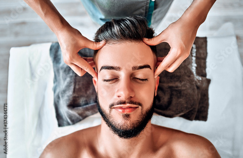 Handsome man having head massage in spa salon