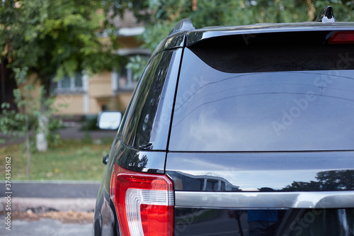 Back window of black car parked on the street in summer sunny day, rear view. Mock-up for sticker or decals © Alexey