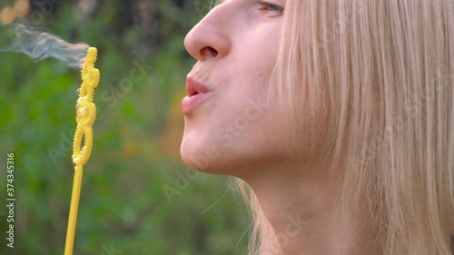 A young woman blows bubbles in nature. A happy young blonde is walking in the Park and blowing soap bubbles on a Sunny day.