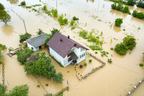 Aerial view of flooded house with dirty water all around it.