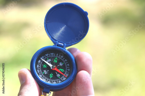 Old classic navigation compass in hand on natural background as symbol of tourism with compass, travel with compass and outdoor activities with compass