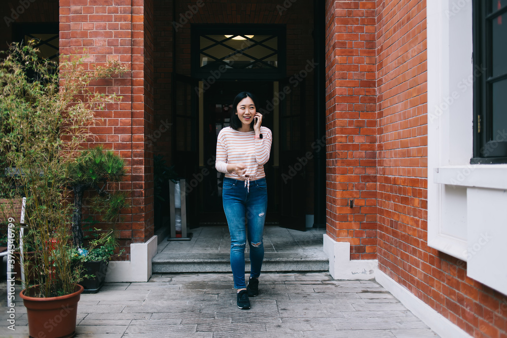 Asian female leaving building and speaking on phone