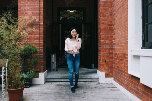 Asian female leaving building and speaking on phone