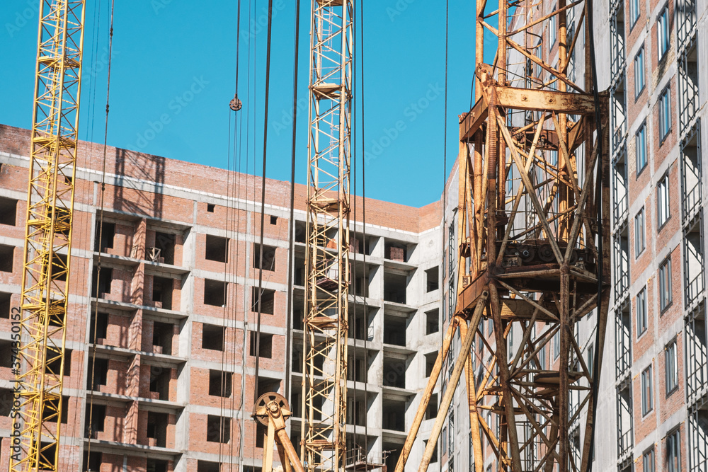 tower crane at a building site during the construction of blocks of flats. Detail of residential building under construction. Concrete structure with metal struts. 