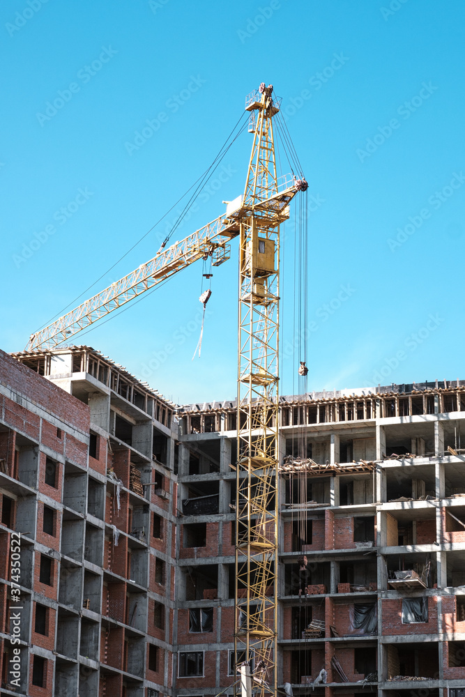 tower crane at a building site during the construction of blocks of flats. Detail of residential building under construction. Concrete structure with metal struts. 