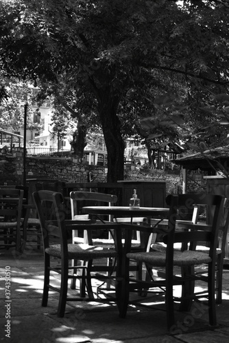table and chairs in a cafe (in the central square of a village) (black & white)
