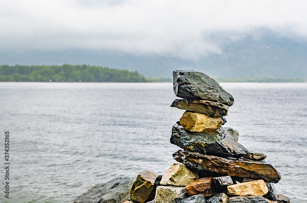 various stones stacked on top of each other in the form of a pyramid lie on the shore of the lake in foggy rainy weather various stones stacked on top of each other in the form of a pyramid lie on the shore of the lake in foggy rainy weather