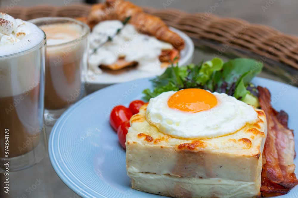Ham and cheese sandwich with bechamel sauce and topped with a fried egg, known as Croque-madame. Croque madame sandwich on the table. Hot french toasts with ham, melted emmental cheese and fried egg. Ham and cheese sandwich with bechamel sauce and topped with a fried egg, known as Croque-madame. Croque madame sandwich on the table. Hot french toasts with ham, melted emmental cheese and fried egg.