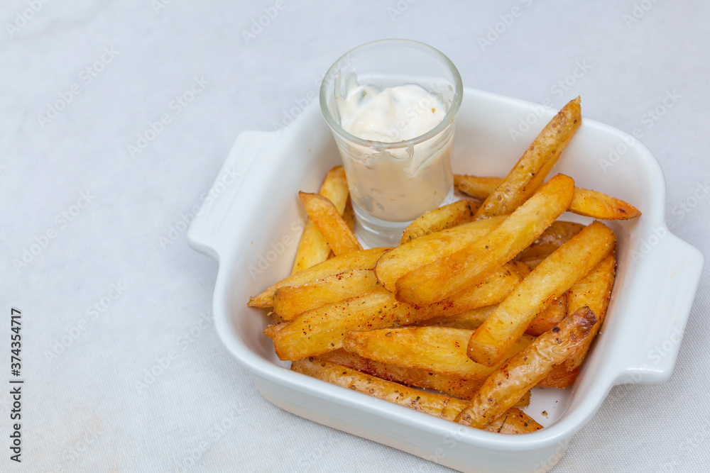 Crispy Potato French Fries in white bowl. French fries with dip sauce closeup on the table. Homemade Baked Potato Fries with Mayonnaise on white bowl. Close up Tasty Fried potato snacks in bowl. Crispy Potato French Fries in white bowl. French fries with dip sauce closeup on the table. Homemade Baked Potato Fries with Mayonnaise on white bowl. Close up Tasty Fried potato snacks in bowl.
