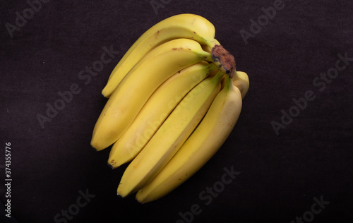 Bananas. A branch of natural bananas on a black background.