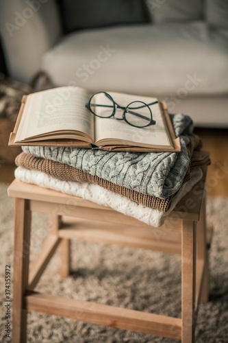 Toned photo. Autumn decor. Knitted sweaters, book, glasses . Cozy. Autumn.