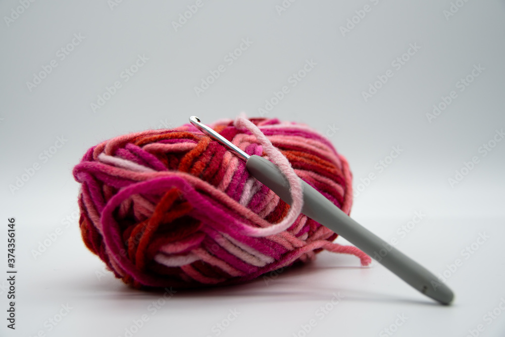 A brightly colored ball of wool with warm colors and a crochet hook